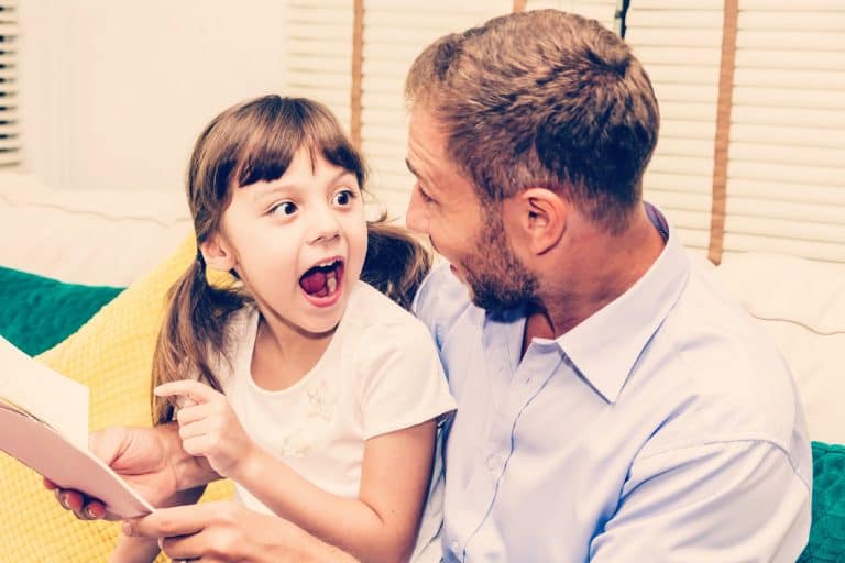 Niña se sorprende y señala un libro con su padre