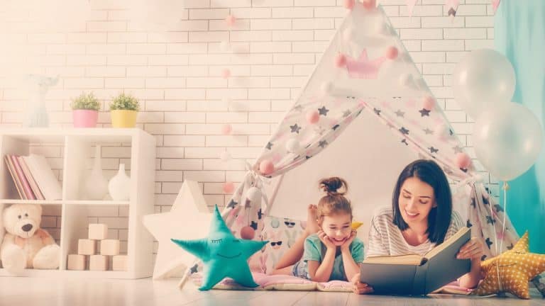 Madre e hija leen un libro bajo un tipi