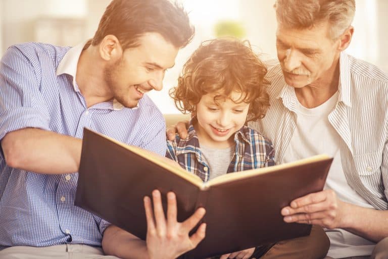 Niño leyendo un libro con su padre y su abuelo