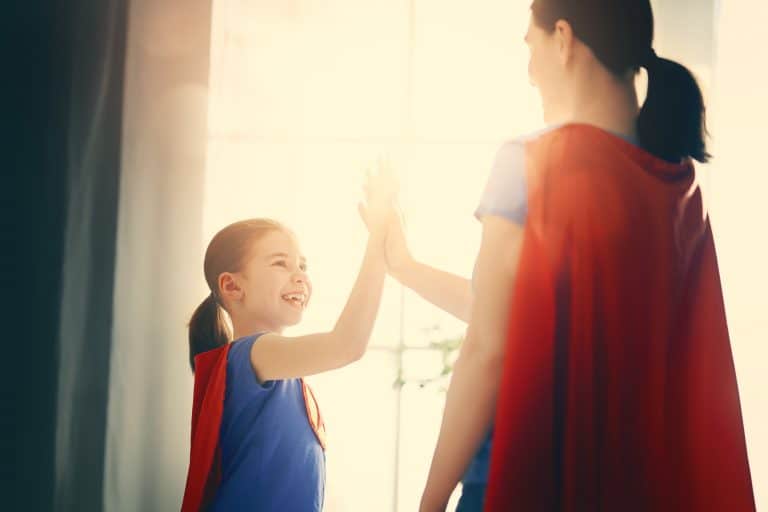 Madre e hijas chocan las manos con capas de superheroínas