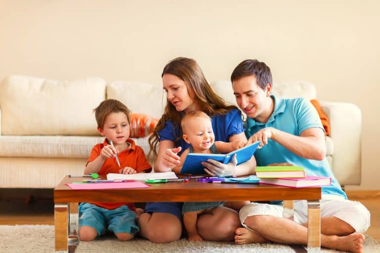 Young family with two kids drawing and reading together