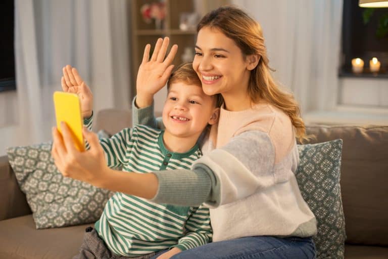 family, technology and people concept - happy smiling mother and little son with smartphone having v