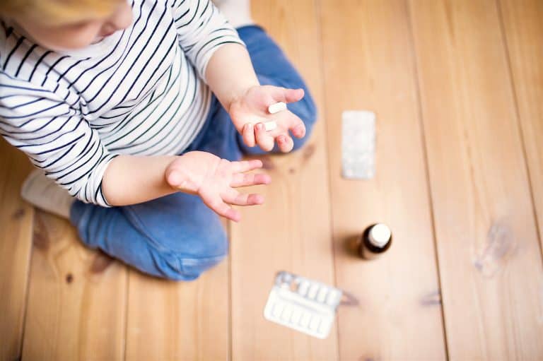 Little Toddler Playing With Pills. Domestic Accident. Dangerous Situation At Home. Top View.