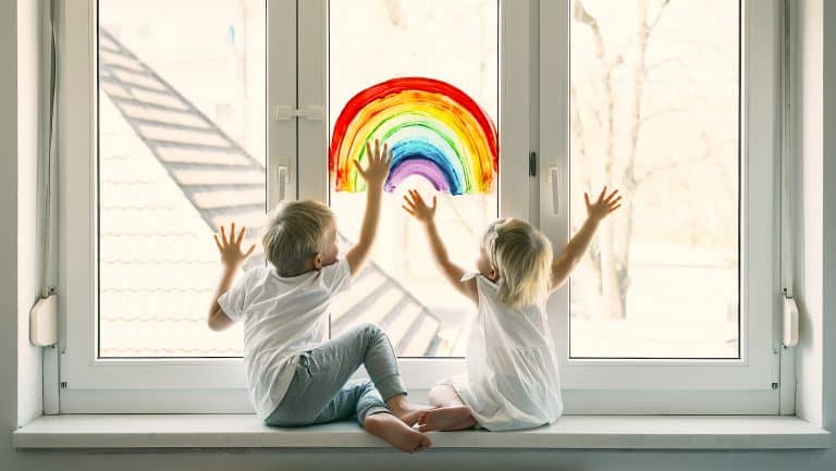 Little Children On Background Of Painting Rainbow On Window. Photo Of Kids Leisure At Home. Positive